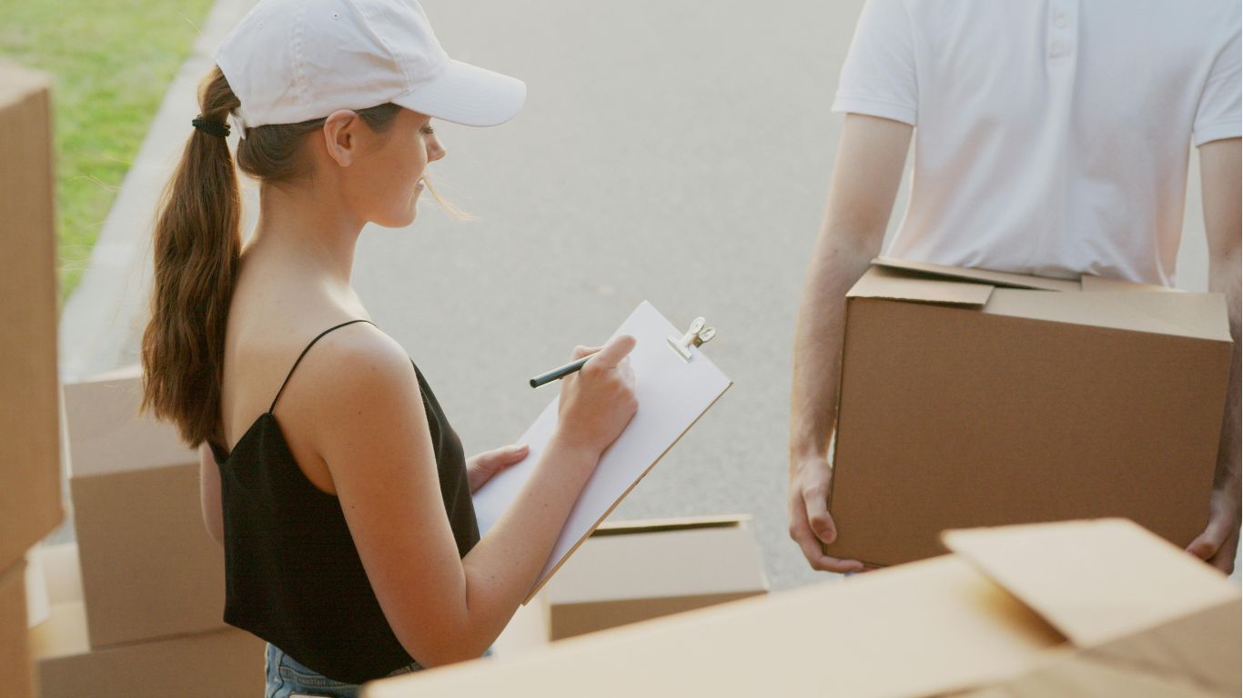 Two movers carrying furniture outside a building in Dubai, UAE.