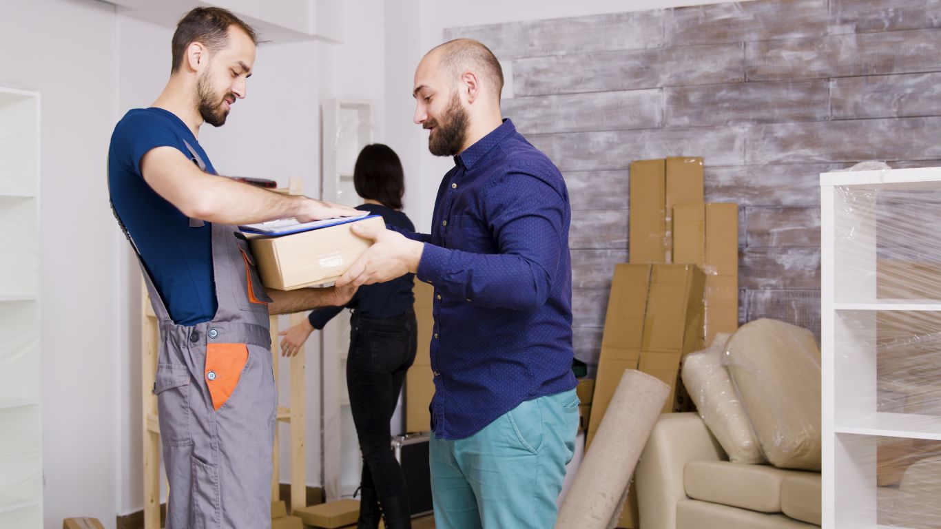 Two movers loading boxes onto a moving truck in Al Ain, UAE.